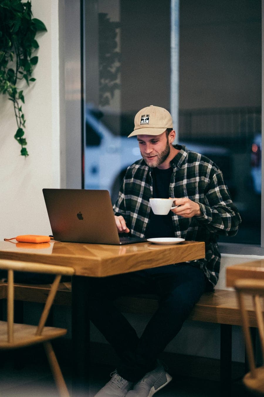 Man sitting with a coffee while working on a laptop